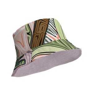 Può includere: Un cappello a secchiello con un motivo astratto colorato in verde, marrone, rosa e bianco. Il cappello ha un lato inferiore di colore lilla chiaro.