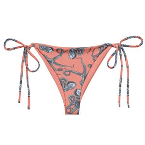 Puede incluir: Braga de bikini de color rosa coral con un diseño de nudo lateral. La tela presenta un patrón repetido de ilustraciones de pulpos negros y grises.