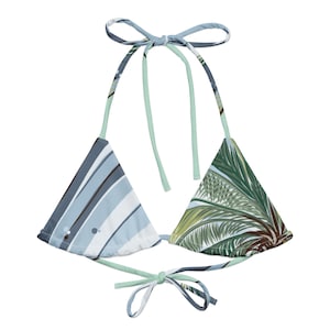 Puede incluir: Un top de bikini triangular de estampado azul y verde con tirantes ajustables. El top tiene un estampado tropical en un lado y un estampado a rayas en el otro.