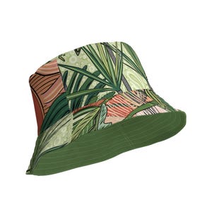 Può includere: Un cappello a secchiello verde con stampa a foglie tropicali. Il cappello ha un'ampia tesa e una corona piatta.
