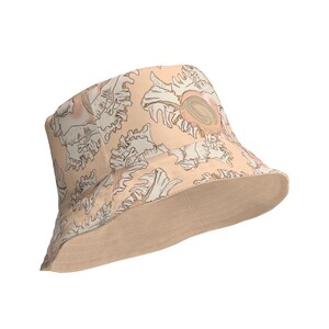 Può includere: Un cappello a secchiello beige con un motivo di conchiglie bianche e rosa.