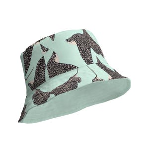 Può includere: Un cappello a secchiello blu chiaro con un motivo di razze macchiate di nero e bianco.