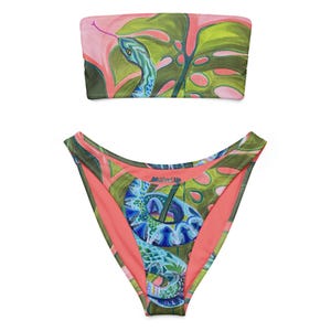 May include: Two-piece swimsuit set featuring a colourful snake and leaf pattern. The top is a bandeau style, and the bottoms are high-waisted. The colour scheme includes pink, green, and blue, creating a tropical aesthetic. The swimsuit is made of a soft, comfortable material.