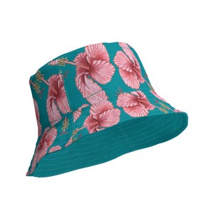 Può includere: Un cappello a secchiello blu turchese con una stampa di fiori di ibisco rosa. Il cappello ha un'ampia tesa e una corona piatta.