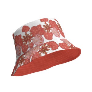 Può includere: Un cappello a secchiello rosso e bianco con una stampa floreale. Il cappello ha un'ampia tesa e un lato inferiore rosso.