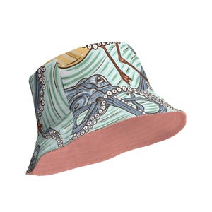 Può includere: Un cappello a secchiello blu e rosa con un design di polpo e fenicottero. Il cappello ha un'ampia tesa e una corona piatta.