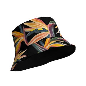 Può includere: Cappello a secchiello nero con una stampa tropicale colorata di uccello del paradiso. Il cappello ha un'ampia tesa e una corona piatta.