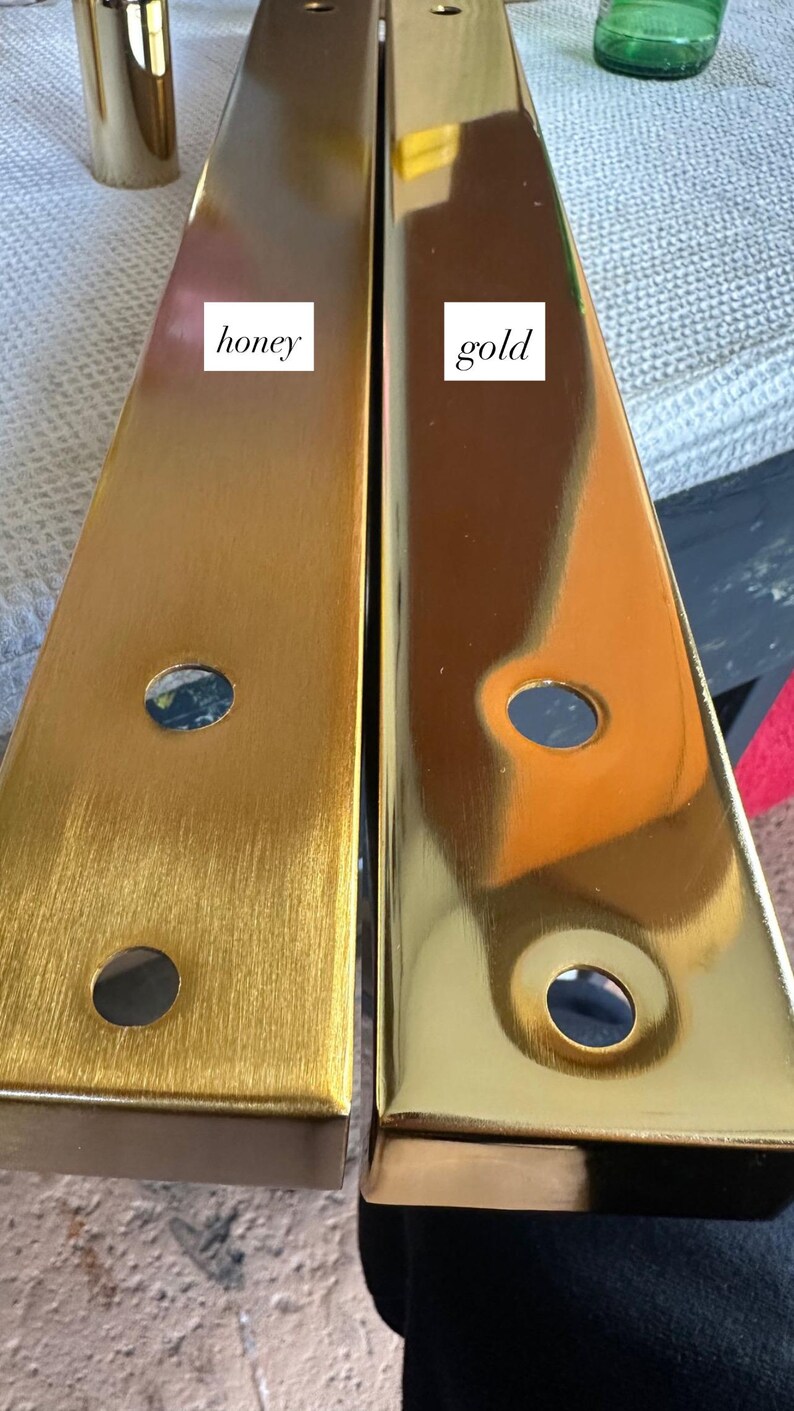 May include: Two rectangular metal furniture legs, one with a honey finish and the other with a gold finish. Each leg has two circular holes. The honey leg has a brushed texture, while the gold leg is highly polished. The word "honey" and "gold" are written on the legs.