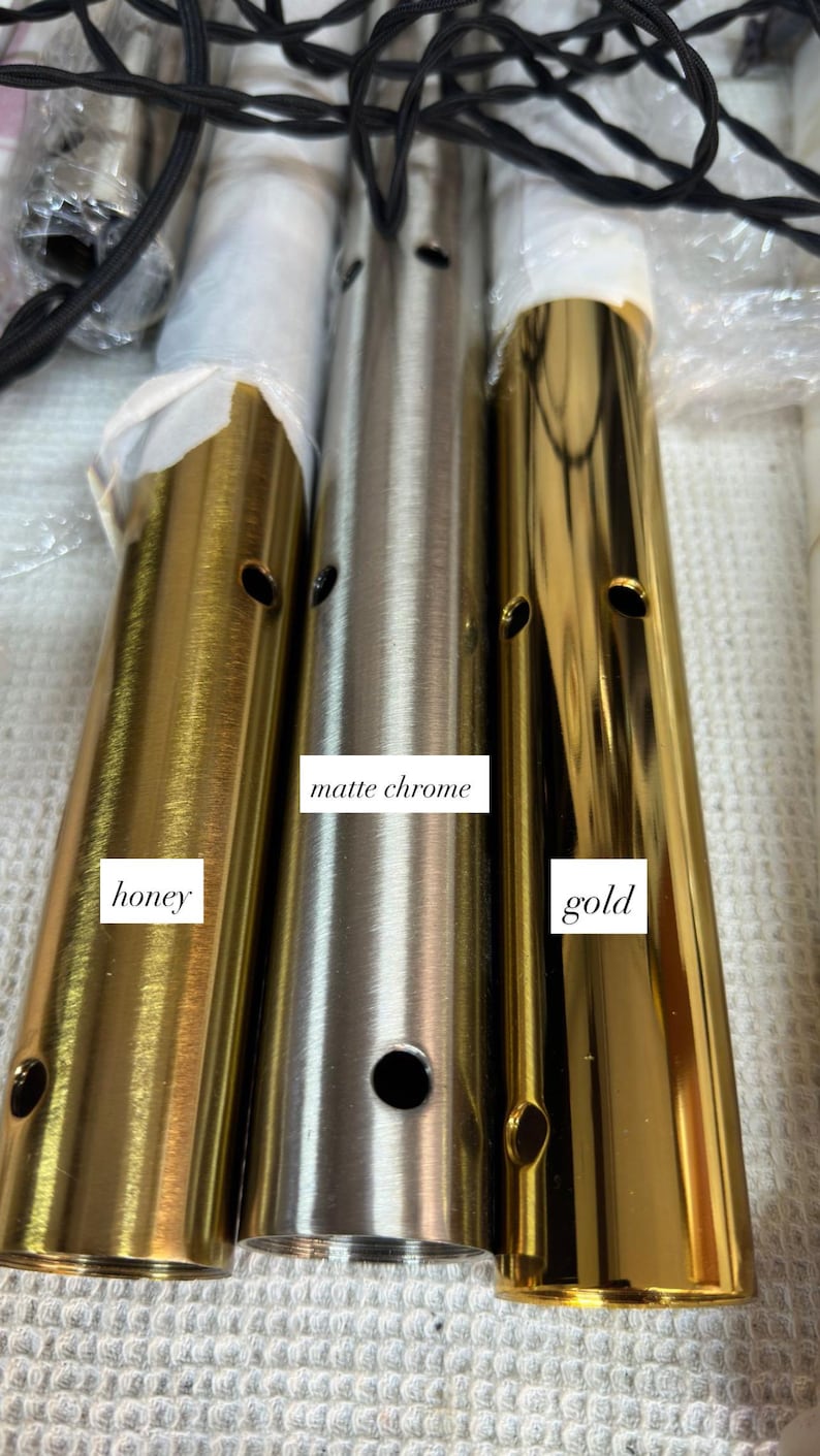 May include: Close-up of three cylindrical metal lamp parts in honey, matte chrome, and gold finishes. Each part has a series of small holes. The honey and gold parts have a shiny finish, while the matte chrome is a muted silver color.