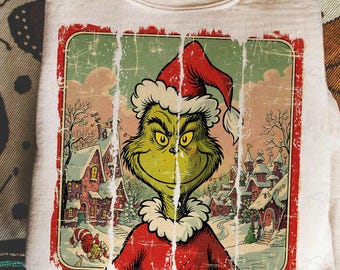 May include: A cream-colored sweatshirt featuring a distressed graphic of the Grinch in a Santa hat, with a snowy Whoville scene in the background. The Grinch is green with yellow eyes and a mischievous grin.