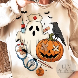 May include: Beige Halloween-themed sweatshirt with a ghost wearing a nurse's hat, a jack-o'-lantern, and a crow. The design includes a syringe, stethoscope, thermometer, and the words "Trick or Treat". Bats are scattered around the design.