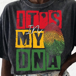 Può includere: T-shirt grigio scuro con la scritta "IT'S IN MY DNA" in lettere a blocchi rosse, gialle e verdi. Un disegno di impronta digitale negli stessi colori è sul lato destro.