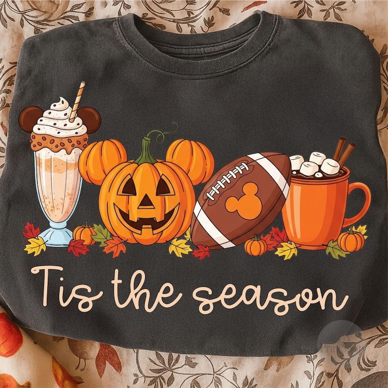 May include: Dark grey sweatshirt featuring a seasonal graphic. The design includes a milkshake, a carved pumpkin, a football, and a mug of hot chocolate. The text "Tis the season" is written in a cursive font.