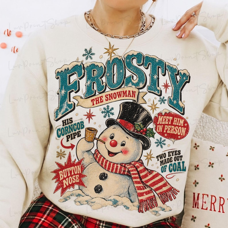 May include: A cream-colored crewneck sweatshirt featuring a graphic of a snowman wearing a black top hat and a red and white striped scarf. The text reads Frosty The Snowman, His Corncob Pipe, Button Nose, Meet Him In Person, and Two Eyes Made Out Of Coal.