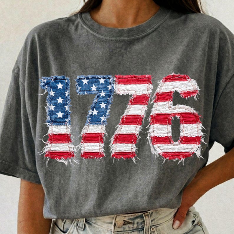 May include: Gray t-shirt with the number "1776" in a distressed American flag design. The numbers are made to look like they are made of denim and have a frayed edge.
