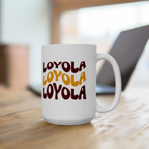May include: White ceramic coffee mug with a brown and gold design that says "LOYOLA" three times.