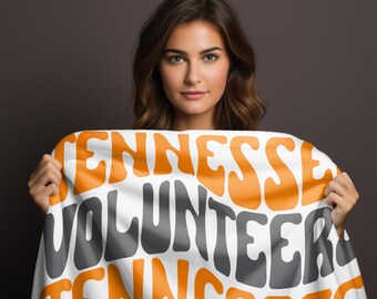 May include: A white fabric banner with the words "Tennessee Volunteer Tennessee" in orange and gray lettering. The banner is being held by a person.
