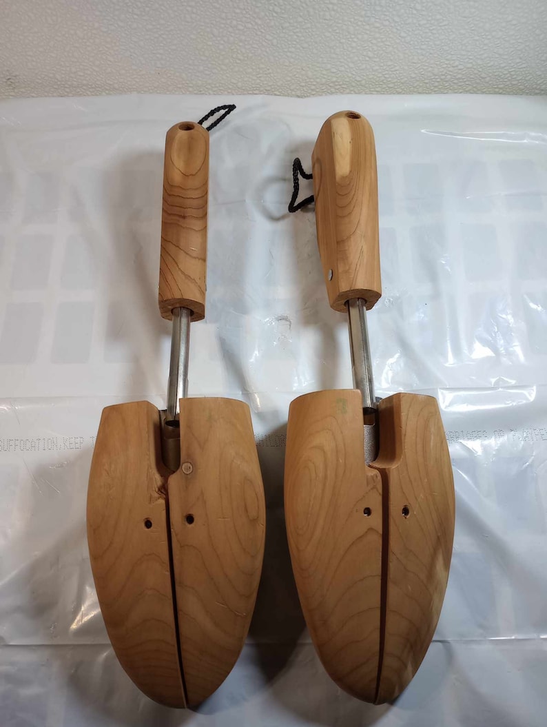 May include: Two wooden shoe trees with metal adjusters. The shoe trees are brown and have a natural wood finish. The shoe trees are designed to help maintain the shape of shoes.