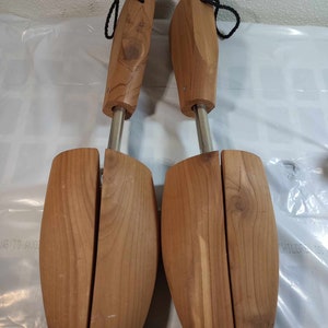 May include: A pair of wooden shoe trees with a metal spring mechanism. The shoe trees are made of light brown wood and have a smooth finish.