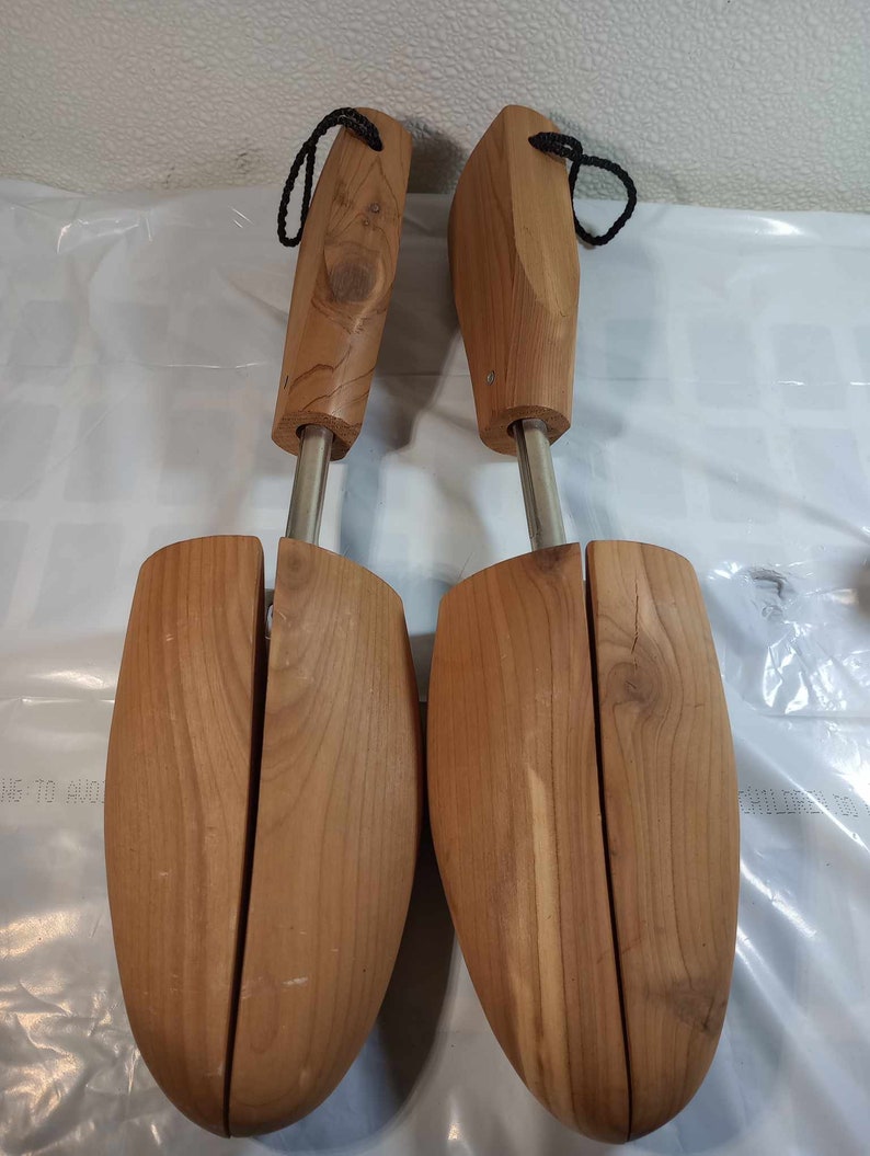 May include: A pair of wooden shoe trees with a metal spring mechanism. The shoe trees are made of light brown wood and have a smooth finish.