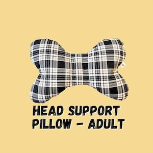 May include: A bone-shaped head support pillow for adults. The pillow features a black, white, and gray plaid pattern. The text "HEAD SUPPORT PILLOW - ADULT" is displayed in bold, black letters.