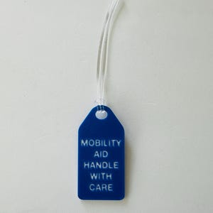 May include: A blue plastic tag with a white string attached. The tag reads "Mobility Aid Handle With Care".