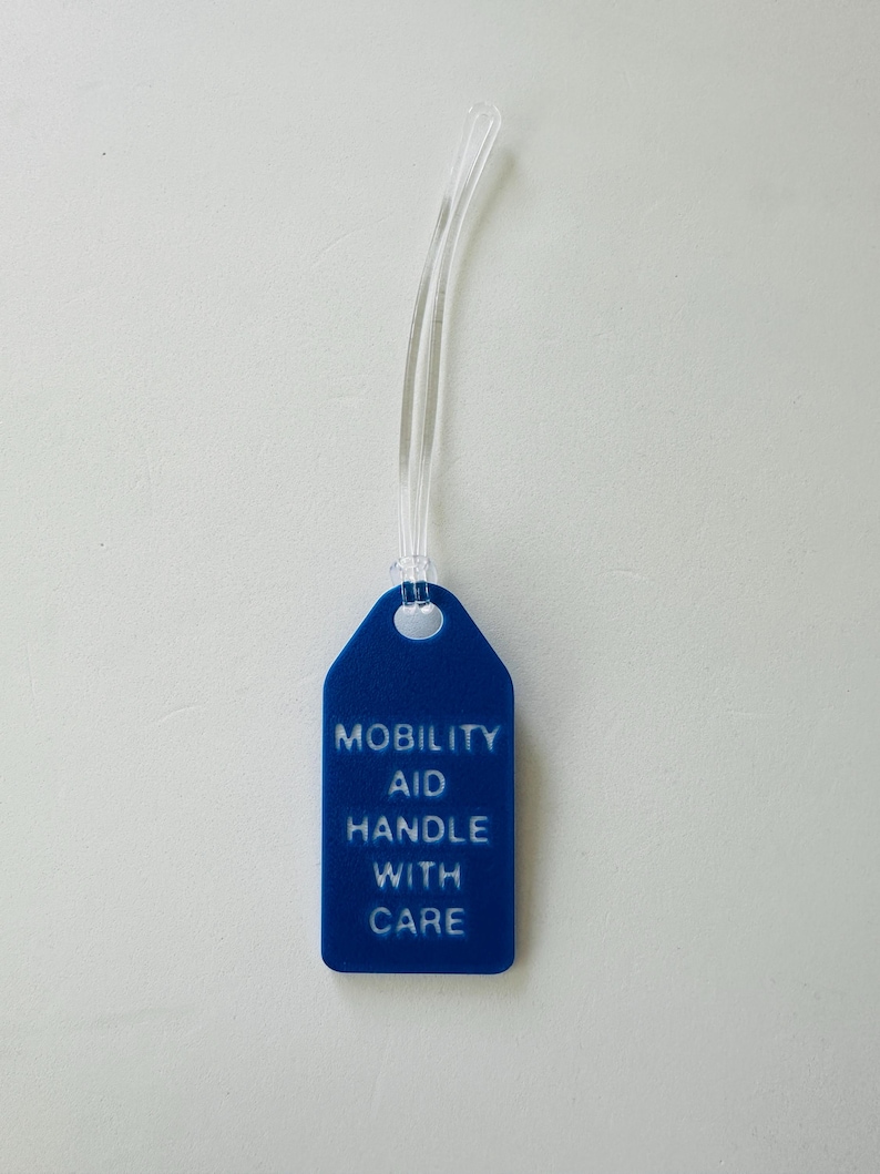 May include: A blue plastic tag with a white string attached. The tag reads "Mobility Aid Handle With Care".