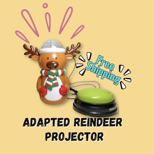 May include: An adapted reindeer projector with a green button and a light-up head. The reindeer has brown antlers, a red and green scarf, and red mittens. The text "ADAPTED REINDEER PROJECTOR" is displayed below the reindeer.