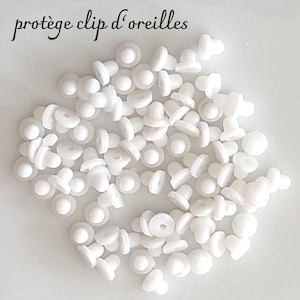 Peut inclure: Un tas de petits protège-clips d'oreilles blancs. Chaque protecteur a une base plate et circulaire et un dessus arrondi en forme de champignon. Le texte "protège clip d'oreilles" est écrit en script noir en haut de l'image.
