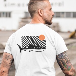 May include: White t-shirt featuring a black and white graphic of a whale shark with a stylised sun behind it.
