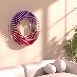 May include: A modern wall art piece featuring a circular design with layered wooden elements. The artwork transitions in color from red to purple. It is mounted on a light pink wall above a white sofa with decorative pillows.