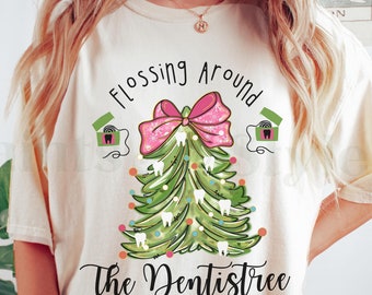 Könnte beinhalten: Ein weißes T-Shirt mit dem Text "Flossing Around The Dentistree" und einem grünen Weihnachtsbaum mit einer rosa Schleife und weißen Zahnschmuck.