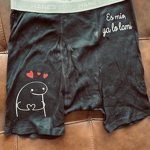 Puede incluir: Bóxer negro con cintura gris con la marca "Hanes". El bóxer presenta un personaje de dibujos animados blanco sosteniendo un corazón y el texto "Es mío, ya lo lamí" en blanco.