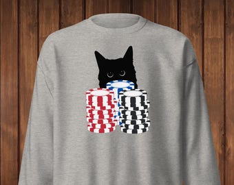 May include: A light gray sweatshirt featuring a black cat peeking over stacks of poker chips. The chips are red and white, blue and white, and black and white. The sweatshirt is a casual garment.