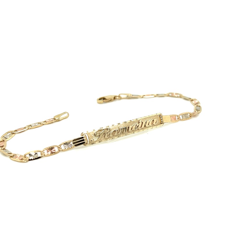 May include: A gold bracelet with a nameplate that reads "Romeina". The bracelet is made of three different colors of gold: yellow, white, and rose.