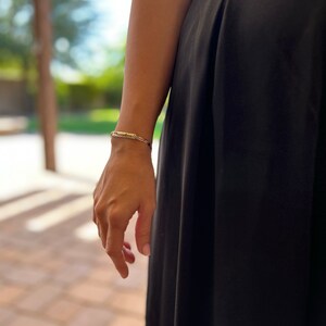 May include: A person wearing a black skirt and a silver bracelet on their wrist.