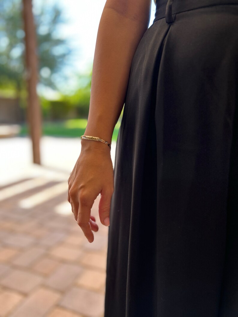 May include: A person wearing a black skirt and a silver bracelet on their wrist.