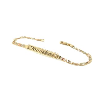 May include: A gold bracelet with a nameplate that reads "Kamelia". The bracelet is made of three different colors of gold: yellow, white, and rose.