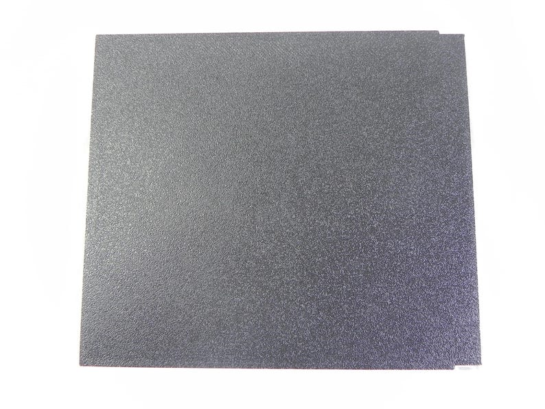 May include: Two gray, textured, square sheets of material are stacked on a white background. The sheets have a speckled appearance and a slightly rough surface. The edges are clean and straight.