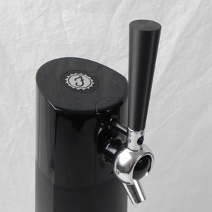 May include: A black countertop beer dispenser with a silver tap and a black handle. The dispenser has a circular logo with the letter "F" inside.