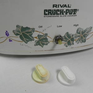 May include: White Rival Crock-Pot stoneware slow cooker with a green vine design. The slow cooker has a knob with settings for off, low, and high.