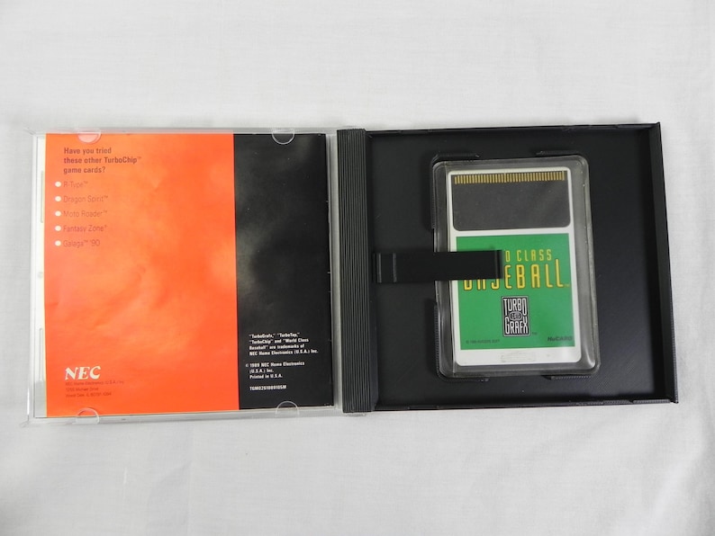 May include: An open black case containing a TurboGrafx-16 video game cartridge labeled "World Class Baseball" and a booklet with orange and black panels. The booklet has the NEC logo and text.