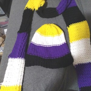May include: A yellow, white, purple, and black striped knitted scarf and matching beanie.