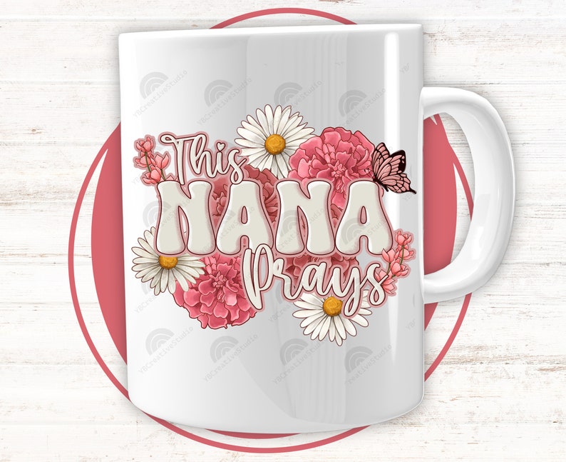 K&ouml;nnte beinhalten: Wei&szlig;e Keramiktasse mit floralem Design und dem Text "This Nana prays".