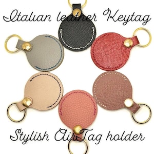 May include: Six different coloured leather keyrings with a gold ring and a button. The keyrings are round and have a stitched edge. The text "Italian leather Keytag" is at the top of the image and the text "Stylish AirTag holder" is at the bottom of the image.