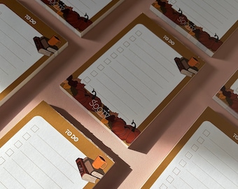 May include: A set of five brown to-do list notepads with a fall theme. Each notepad has a white background with lined paper and a decorative border featuring pumpkins, leaves, and a stack of books with a cup of coffee. The text "to do" and "sooty" are printed on each notepad.