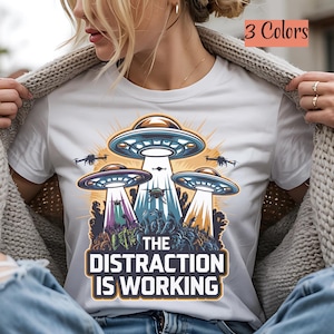 The Distraction Is Working, Funny UFO/Conspiracy T-Shirt - Unisex Tee for Alien Enthusiasts, Conspiracy Theorists, and Humor Fans