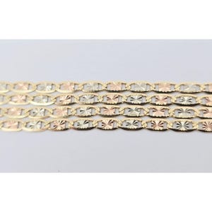 May include: Close-up of three gold-toned chain necklaces. Each chain features an oval link design with starburst-like detailing. The chains are a mix of yellow, white, and rose gold, creating a tricolor effect. The background is plain white.