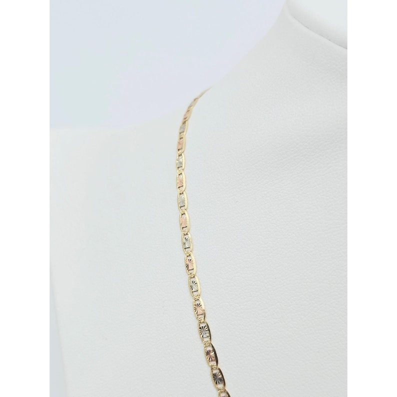 May include: A gold necklace with a delicate chain design. The chain features alternating rectangular and star-shaped links, with a mix of gold, rose gold, and silver tones. The necklace is displayed on a white mannequin.
