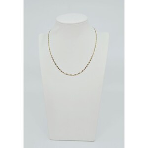 May include: A delicate gold-colored necklace displayed on a white mannequin. The necklace features a fine chain with small, rectangular links. The pendant-free design offers a minimalist and elegant aesthetic, suitable for everyday wear or special occasions.